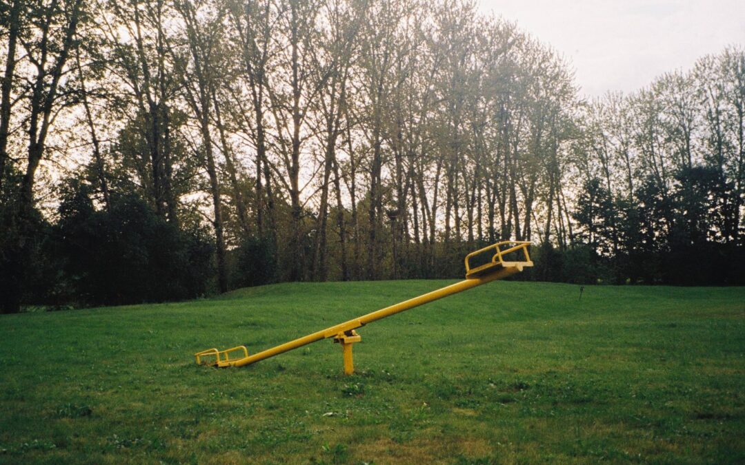 an image of a yellow seesaw in a grassy field